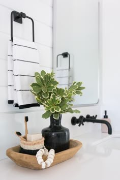 a bathroom sink with a plant in a vase on the counter and towels hanging above it