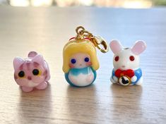 three little toy animals sitting next to each other on a wooden table with a keychain