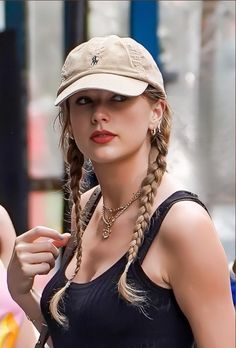 a woman wearing a hat and braids on the street