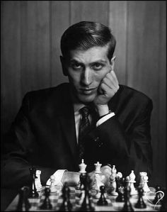 a man sitting at a chess table with his hand on his chin and looking to the side