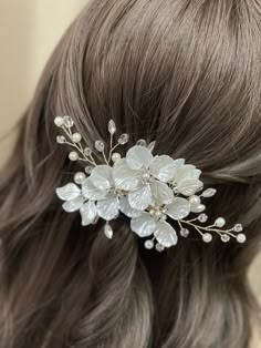 a close up of a woman's hair wearing a white flower and leaf comb