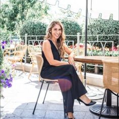 a woman sitting on a chair in front of a table with chairs and umbrellas