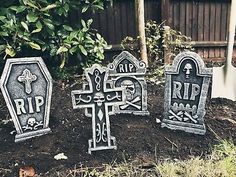 three tombstones sitting in the dirt near some bushes