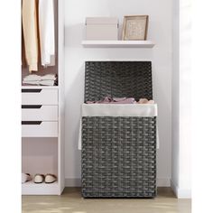 a wicker laundry hamper sitting on top of a wooden floor next to a white shelf