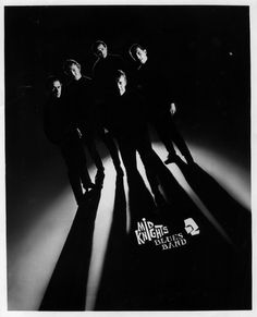 black and white photograph of five men standing in the shadows