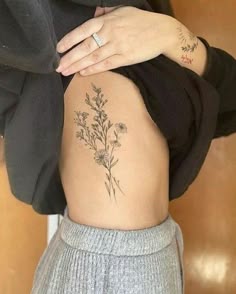 a woman's lower back tattoo with flowers on her ribs and the bottom part of her stomach