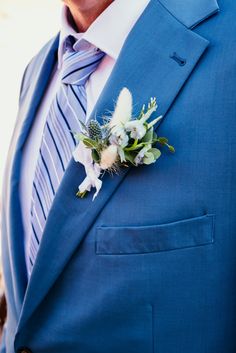 a man wearing a blue suit and tie with flowers in his lapel flower pin