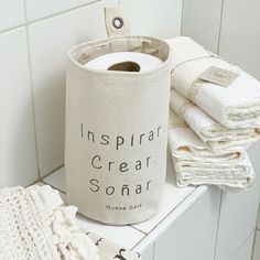 several towels are stacked on a shelf next to a canister with the words inspirer cream sonar printed on it