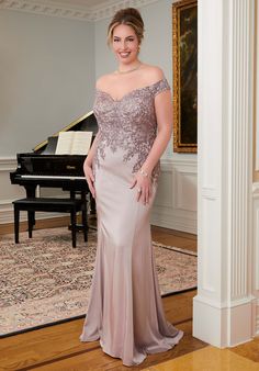 a woman standing in front of a piano wearing an off the shoulder dress with sequins