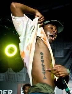 a man with tattoos on his chest and shirt over his shoulder at a music festival