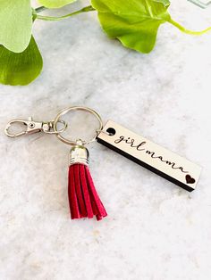 a red tasseled keychain with a name tag attached to it on a marble surface