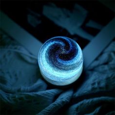 a spinning yarn ball sitting on top of a bed in the middle of the night