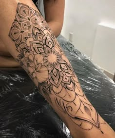 a woman sitting on top of a bed next to a black and white flower tattoo