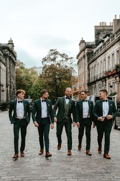 Groom & his groomsmen wear deep green suits & black bow-ties with Brogues Green Suit Men Wedding Groomsmen, Dark Green Groom Suit Grey Groomsmen, Deep Green Groom Suit, Wedding Green Suits Men, Black Green Groomsmen Attire, Groom And Groomsmen Attire Emerald Green, Green Groomsman And Bridesmaid, Dark Green Tuxedo Wedding Groom Style, Green Suit For Wedding Groom