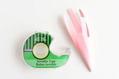 a pair of pink scissors next to a tape dispenser on a white surface