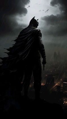 the dark knight standing on top of a hill in the rain with his cape open