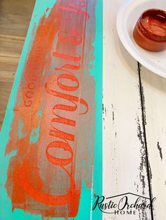 an orange and red sign sitting on top of a wooden table next to a white plate