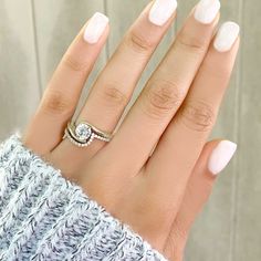 a woman's hand with white manicured nails and a ring on her finger