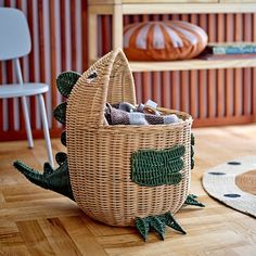 a wicker basket filled with clothes sitting on top of a wooden floor