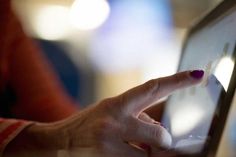 a woman's hand is touching the screen of her laptop computer while she uses it