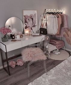 a white desk topped with a mirror next to a chair and pink flowers on top of it