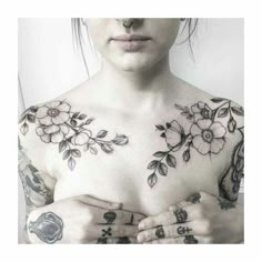 a woman with tattoos on her chest is holding her hands in front of her chest