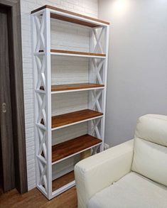 a white chair sitting in front of a book shelf next to a wall with shelves on it