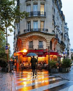 a person with an umbrella is walking down the street in the rain outside some buildings