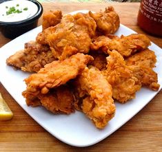 fried chicken on a white plate next to dipping sauce