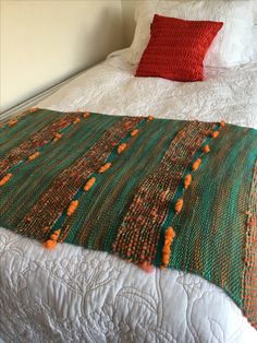 a bed with a white comforter and red pillows