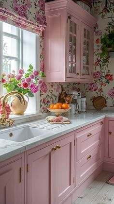 a kitchen with pink cabinets and flowers on the window sill, white counter tops