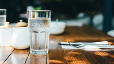 a glass of water sitting on top of a wooden table