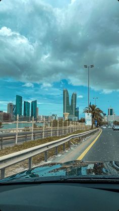 the view from inside a car looking out at a highway and skyscrapers in the distance