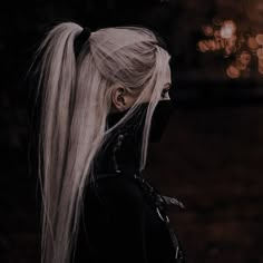 a woman with long white hair wearing a black mask and looking off into the distance