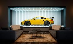 a yellow sports car is on display in a room with two couches and a coffee table