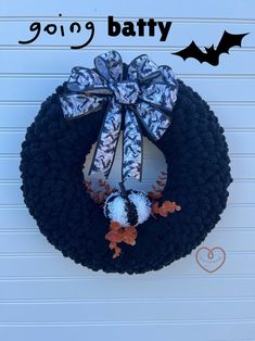 a black wreath with a blue bow and two bats hanging on the side of a garage door