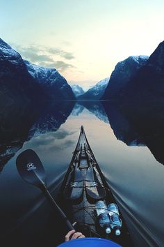 the view from a kayak looking down at mountains and water with snow on them