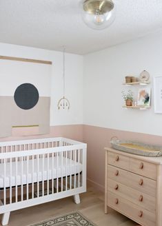 a baby's room with a crib, dresser and wall art on the walls