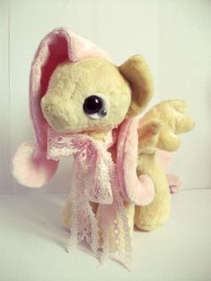 a stuffed animal with a pink scarf around it's neck and eyes, on a white background