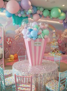 a pink and white popcorn box centerpiece surrounded by pastel balloons