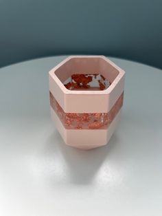 a pink and red vase sitting on top of a white table