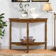 a wooden table with two pictures on the wall above it and a lamp next to it