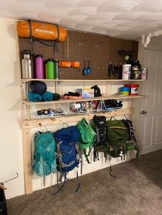 there are many backpacks hanging on the wall in this storage area, and one is empty