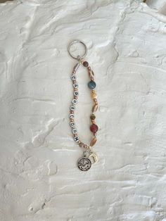 a keychain with beads and charms hanging from it's side on a white surface