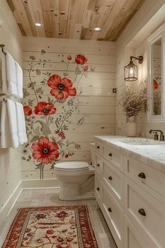 a bathroom decorated in white with red flowers on the wall and rugs underneath it