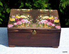 a small wooden box with flowers painted on the top and bottom, sitting on a table