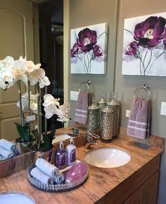 a bathroom with two sinks and paintings on the wall above it's countertop