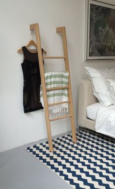 a ladder leaning up against a wall next to a bed with a black and white checkered rug