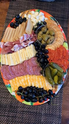 an assortment of cheeses, meats and olives are arranged on a plate