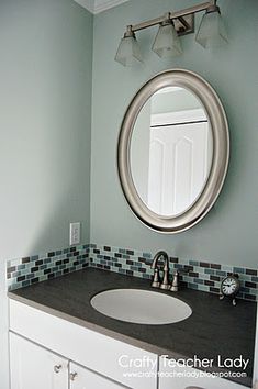 a bathroom sink with a round mirror above it